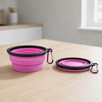 Collapsible purple pet bowl with black rim and carabiner on a wooden surface.
